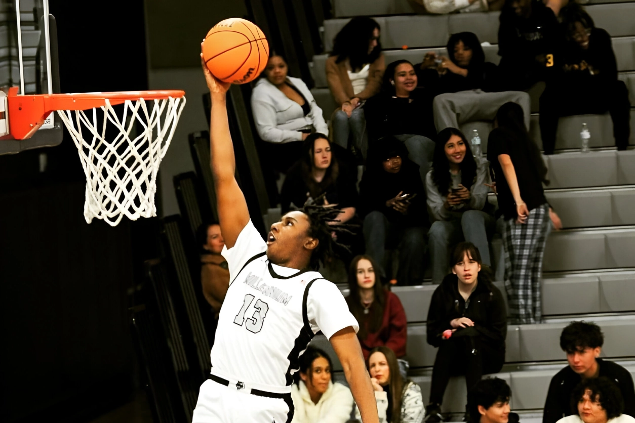 A man in white shirt and black shorts playing basketball.